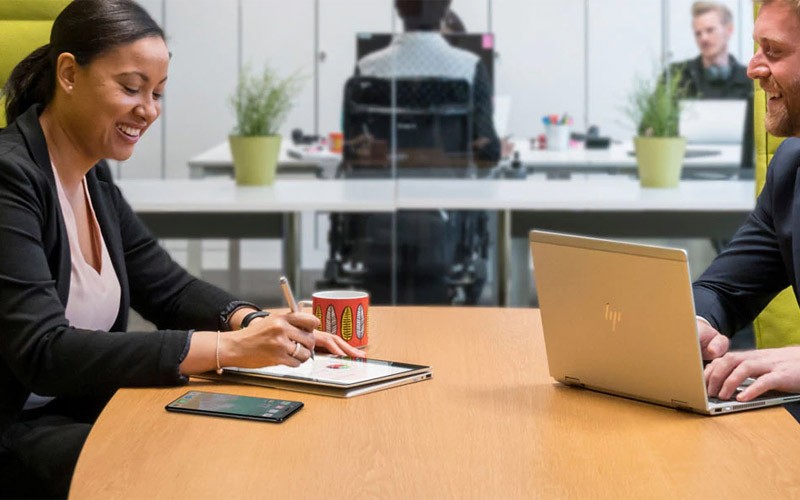 Multiplatform environments can be challenging Two colleagues using HP devices in a meeting